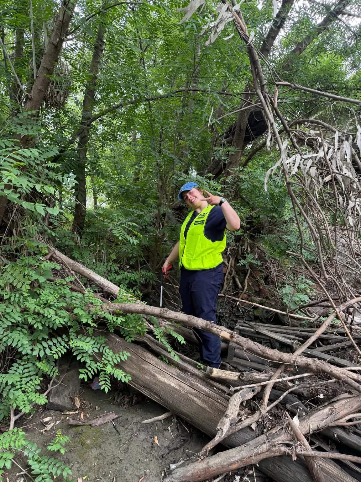 Volunteer in hi-vis clearing rubbish from bushland along the river